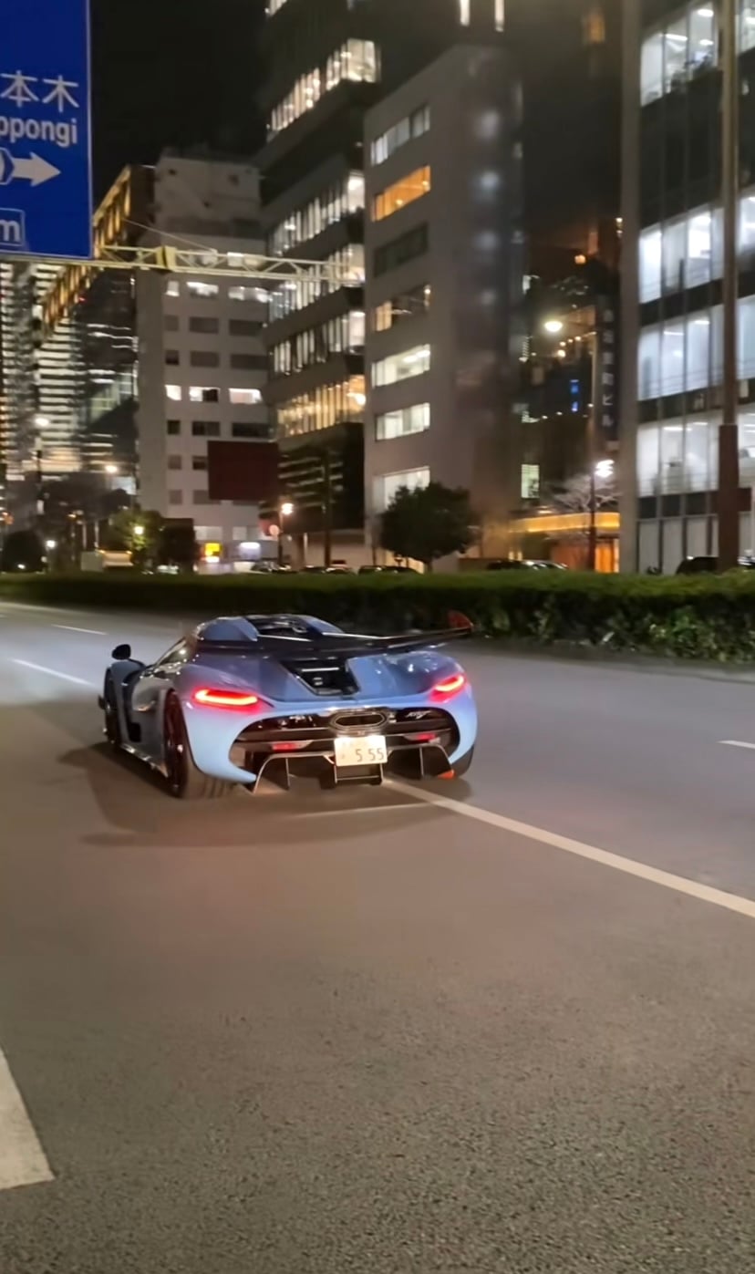 六本木の案内標識の下を走るスーパーカー