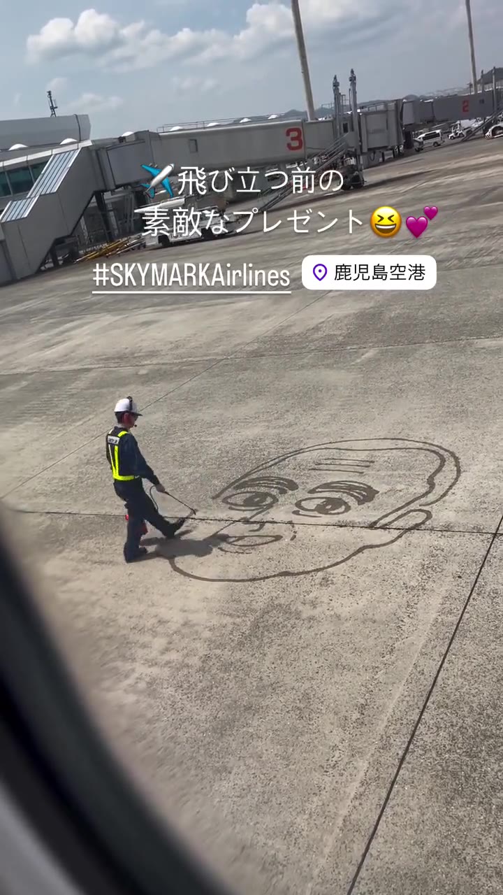 コンクリートの地面に水で顔の絵を描いていく地上係員