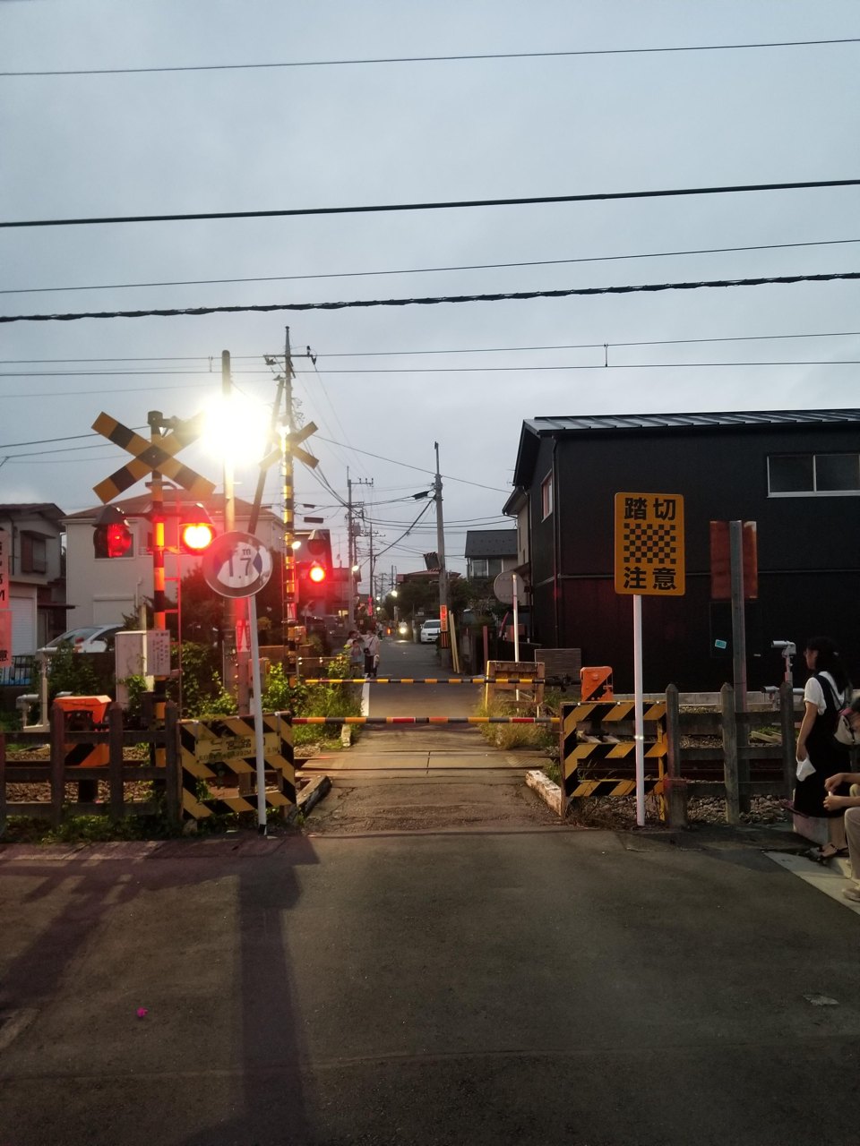 夕暮れの踏切と提灯が灯る参道