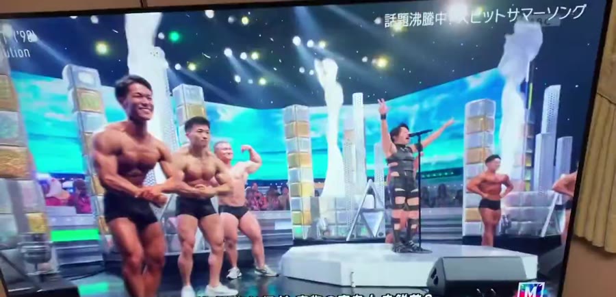 両脇のボディビルダーがポーズを取るステージの様子