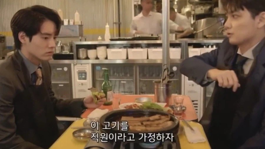 サムギョプサル屋で先輩社員が後輩に肉を見せて話しかける場面