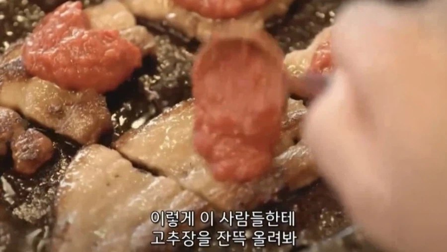 鉄板の上の肉にコチュジャンをたっぷり乗せる手元